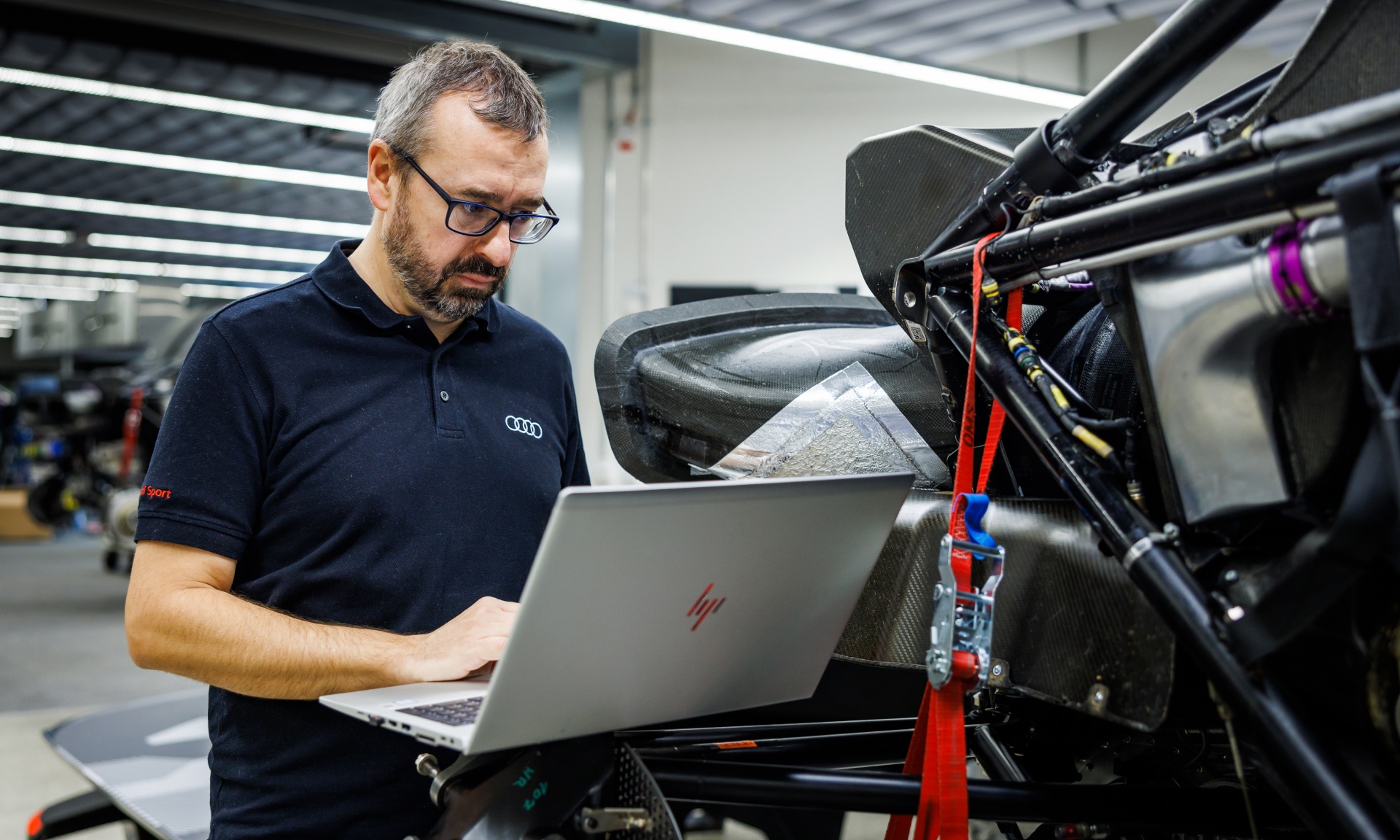 Arnau Nibuó Bosch in a working situation at the computer next to the dismantled Audi RS Q e-tron. 